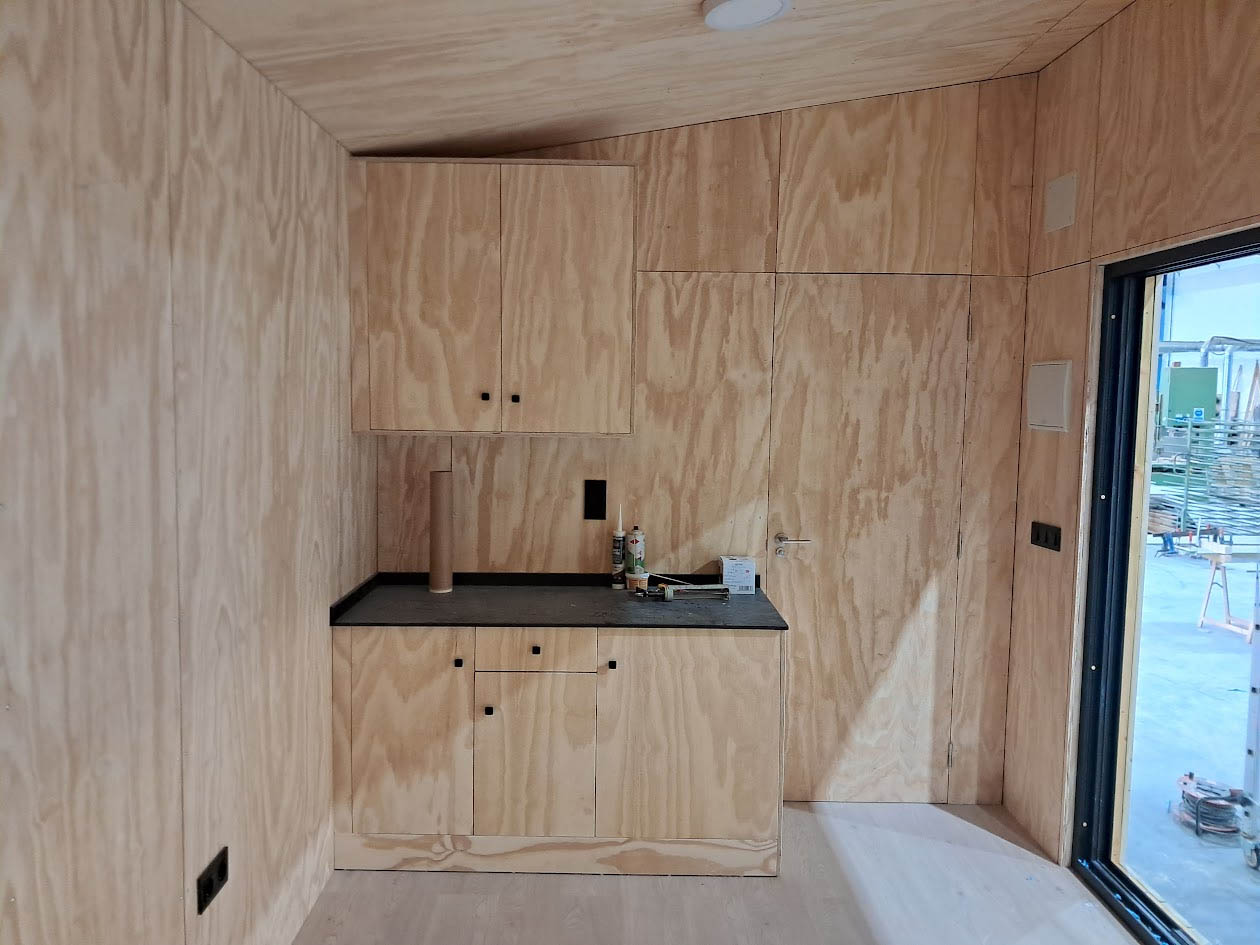 Interior de bungalow modular con revestimientos de madera natural y distribución diáfana optimizada para máximo confort