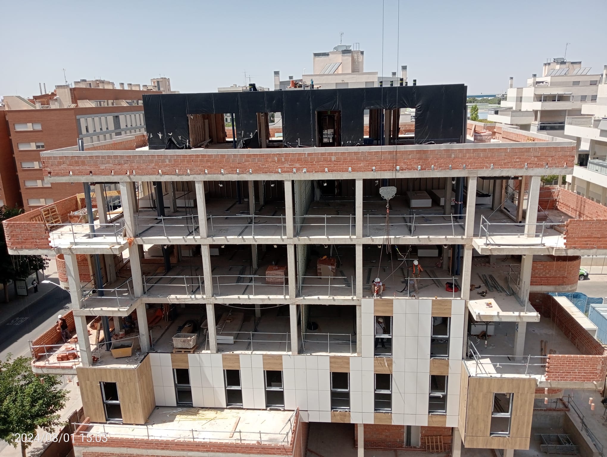 Grúa instalando panel de fachada industrializada prefabricada en edificio residencial durante el proceso de montaje