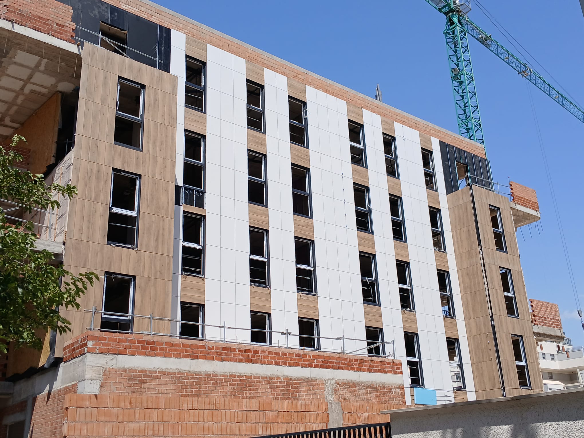 Vista completa del edificio residencial mostrando la integración de la fachada industrializada con el entorno urbano