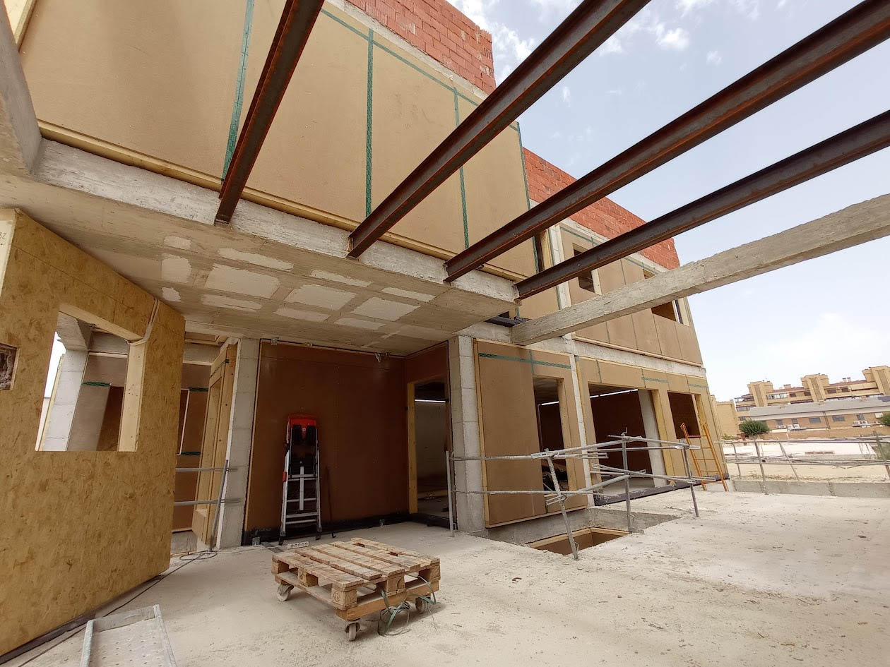Detalle de la combinación harmoniosa entre fachada de madera industrializada y amplios ventanales de cristal de alta eficiencia energética