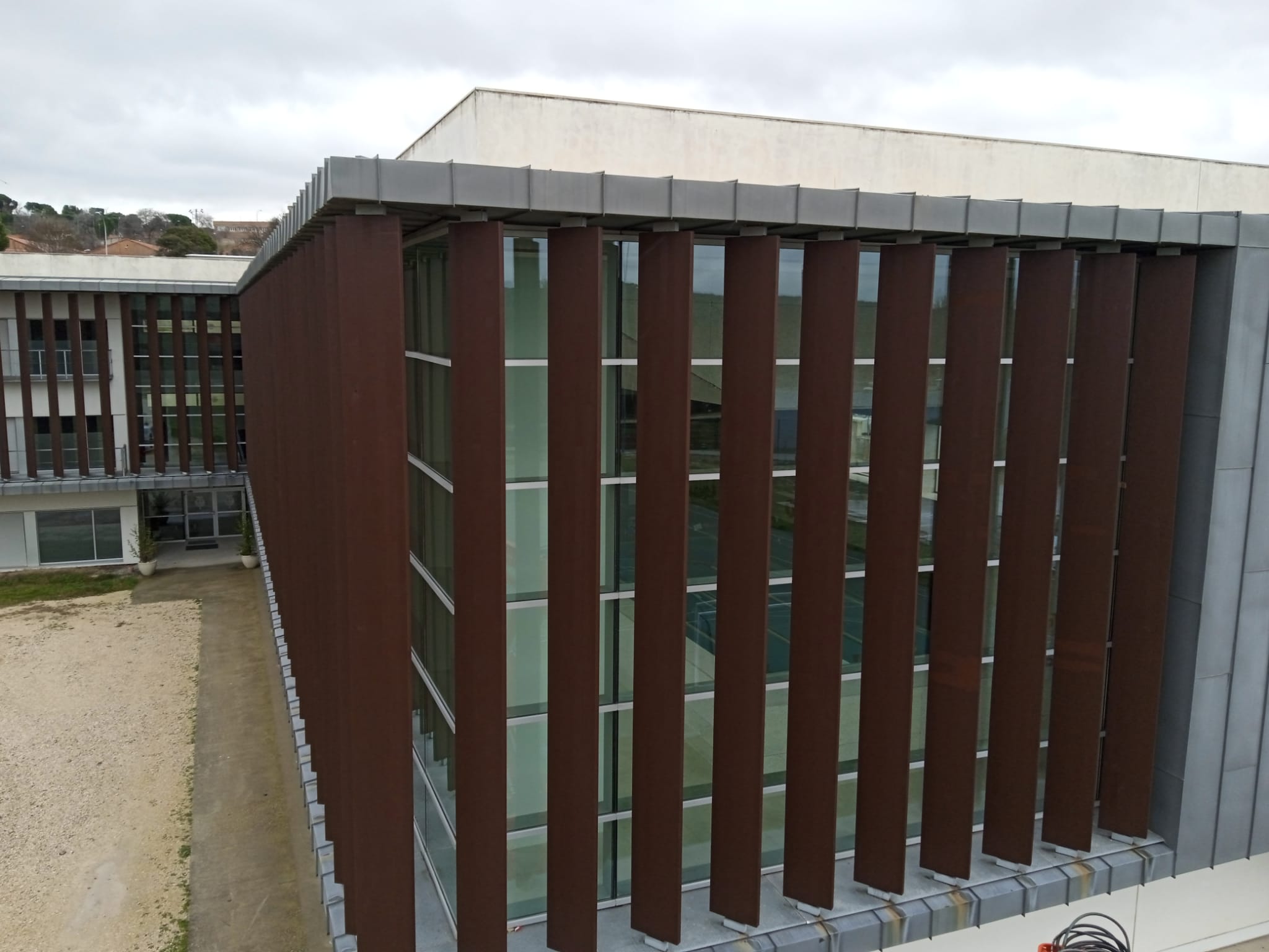 Vista completa del edificio CETSE tras la rehabilitación de lamas mostrando la integración con el entorno urbano